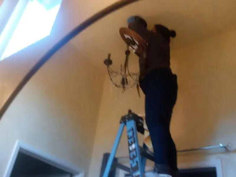 Electrician installing a chandelier in a Mankato residence